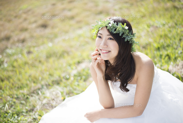 草の上に座るウェディングドレス姿の女性 の写真素材 イラスト素材 アマナイメージズ