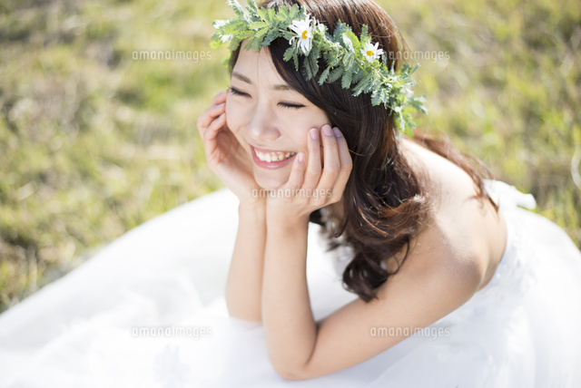 草の上に座るウェディングドレス姿の女性 の写真素材 イラスト素材 アマナイメージズ