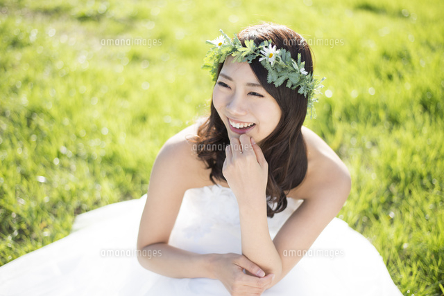 草の上に座るウェディングドレス姿の女性 の写真素材 イラスト素材 アマナイメージズ
