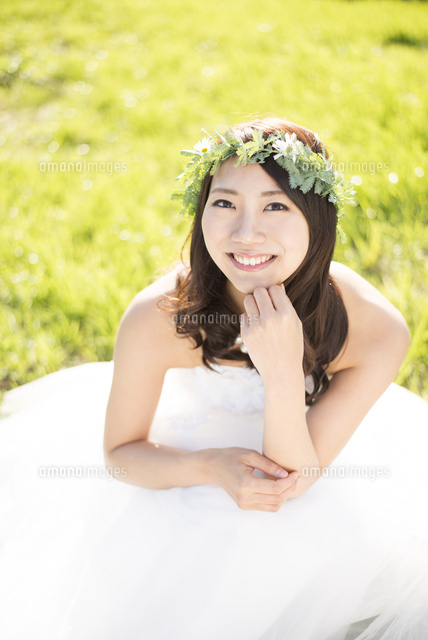 草の上に座るウェディングドレス姿の女性 の写真素材 イラスト素材 アマナイメージズ