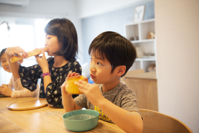 カウンターでパンを食べている子供たち[10568006054]の写真・イラスト
