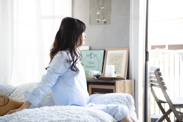 ベッドに座って窓の外を見ている女性[10568006513]の写真・イラスト