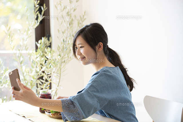スマホで写真を撮っている女性 の写真素材 イラスト素材 アマナイメージズ