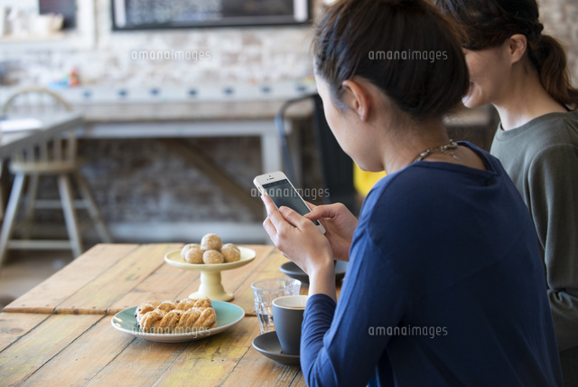 カフェでスマホを使ってスイーツの写真を撮っている女性 の写真素材 イラスト素材 アマナイメージズ
