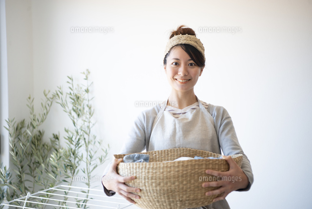 洗濯物の入ったかごを持っている女性 の写真素材 イラスト素材 アマナイメージズ