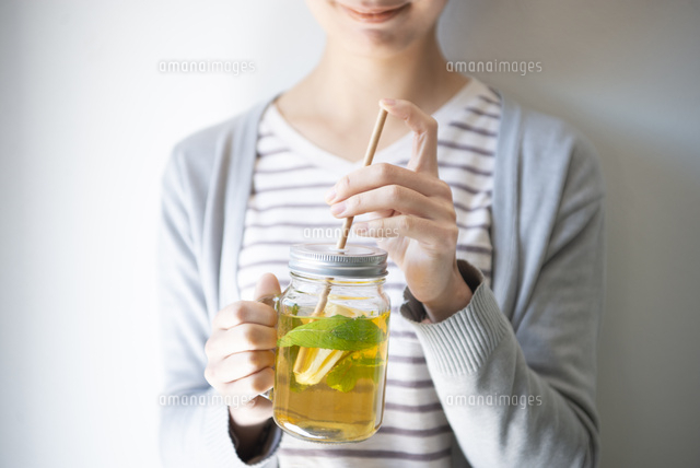 アイスレモンティーと紙ストローを持っている女性 の写真素材 イラスト素材 アマナイメージズ