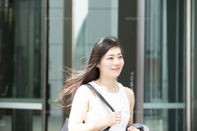 外を歩いているノースリーブ姿の女性 の写真素材 イラスト素材 アマナイメージズ