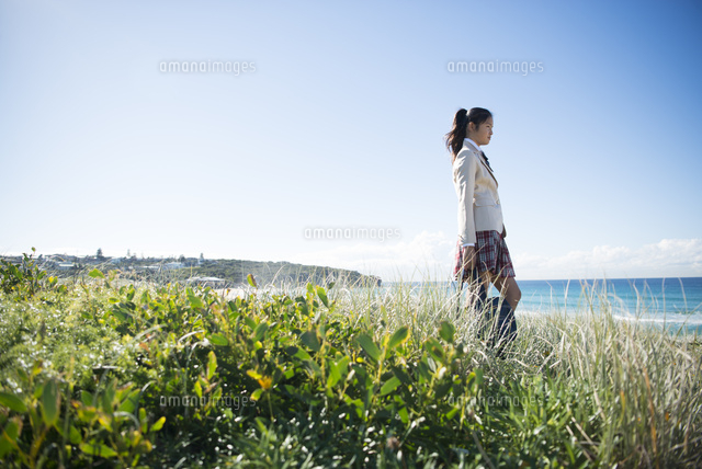 草むらに立っている制服姿の女子学生 の写真素材 イラスト素材 アマナイメージズ