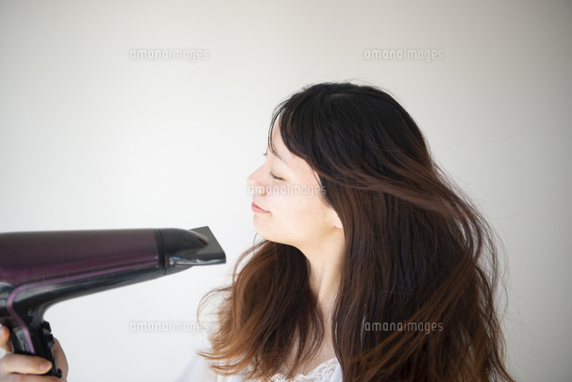 ドライヤーをかけている女性 の写真素材 イラスト素材 アマナイメージズ