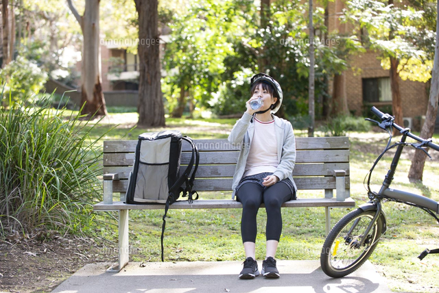 自転車に乗ったフードデリバリーの配達員の後ろ姿 の写真素材 イラスト素材 アマナイメージズ