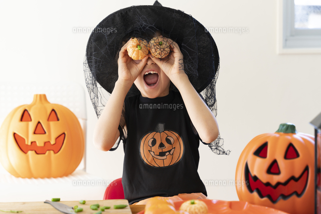 ハロウィンのコスチュームを着てみかんでできたかぼちゃを持って