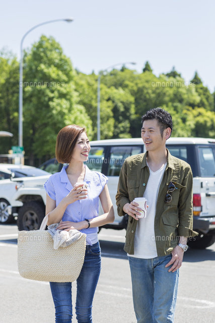 屋外駐車場でコーヒーを飲む代30代カップル の写真素材 イラスト素材 アマナイメージズ