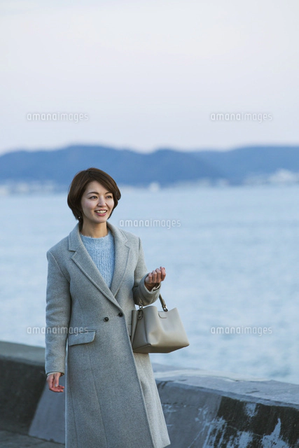 海沿いを歩く笑顔の30代女性[10626002195]の写真・イラスト素材