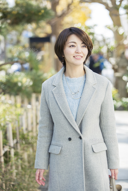 屋外を歩く笑顔の30代女性 の写真素材 イラスト素材 アマナイメージズ