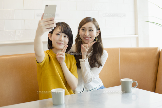スマホで自撮りをする代女子2人 の写真素材 イラスト素材 アマナイメージズ
