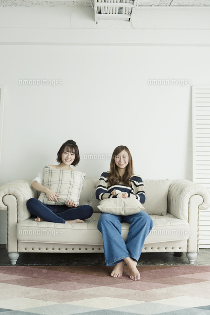 部屋のソファーでくつろぐ代女性2人 の写真素材 イラスト素材 アマナイメージズ