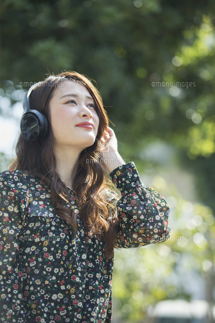 ヘッドホンに手を当てる笑顔の代女性 の写真素材 イラスト素材 アマナイメージズ