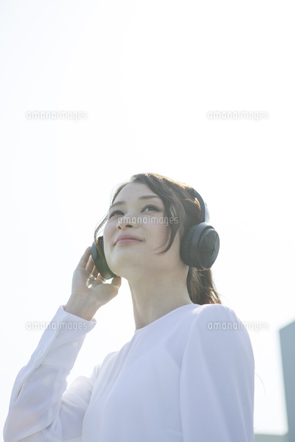 ヘッドホンに手を当てる笑顔の代女性 の写真素材 イラスト素材 アマナイメージズ