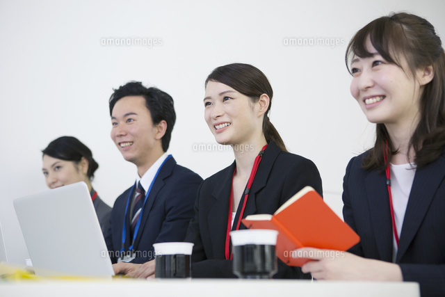 スーツを着て横並びに座る笑顔の男女 の写真素材 イラスト素材 アマナイメージズ