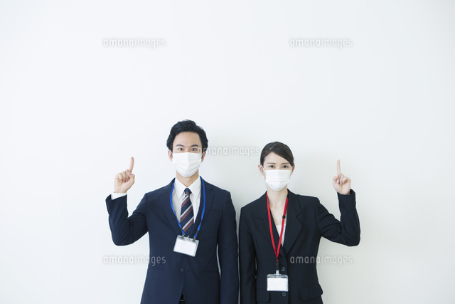 マスクをつけて指差しをするスーツ姿の代男女 の写真素材 イラスト素材 アマナイメージズ