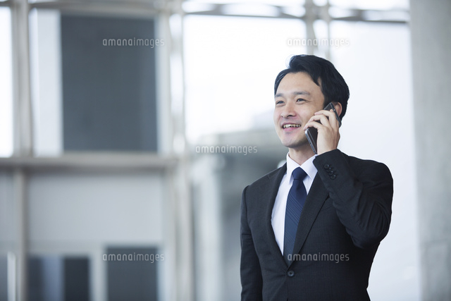 電話をするスーツ姿の笑顔の代男性 の写真素材 イラスト素材 アマナイメージズ