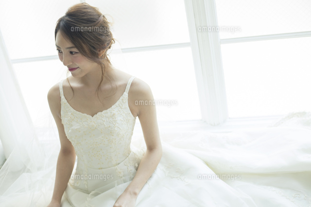窓際に座るウエディングドレス姿の代女性 の写真素材 イラスト素材 アマナイメージズ