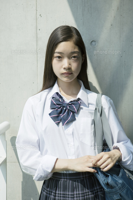 屋外に立つカメラ目線の女子高校生 の写真素材 イラスト素材 アマナイメージズ