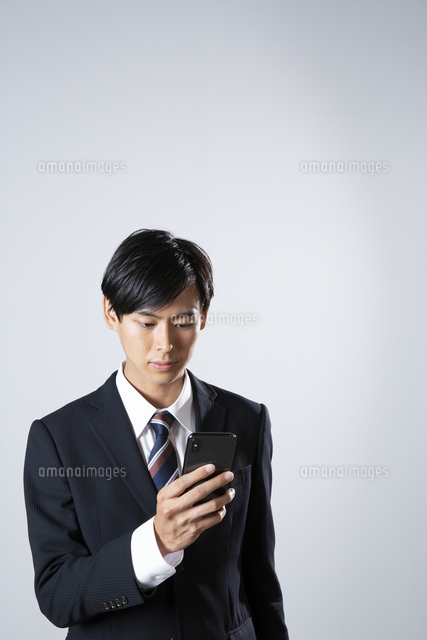 スマホを確認するスーツ姿の20代男性[10626005994]の写真・イラスト  