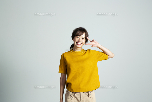 ピースサインをするカメラ目線の20代女性[10626006334]の写真