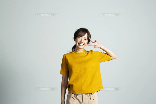 ピースサインをするカメラ目線の20代女性[10626006347]の写真