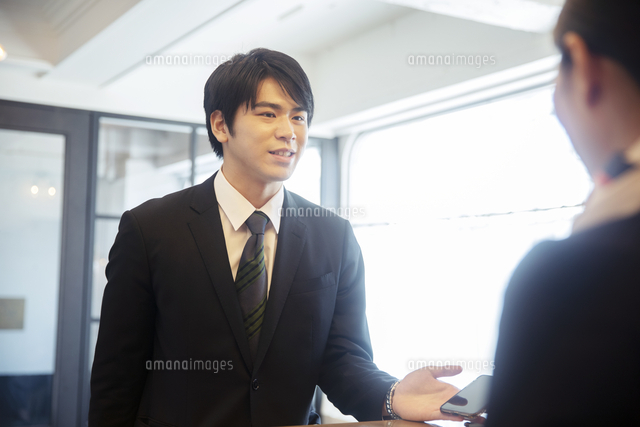 チェックインする男性とコンシェルジュの女性 の写真素材 イラスト素材 アマナイメージズ