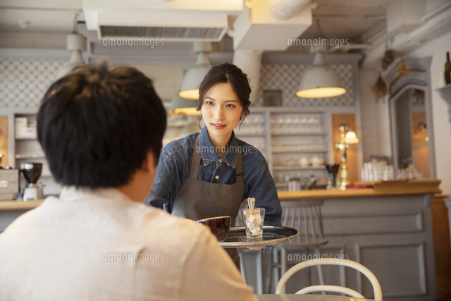 カフェで接客をする女性店員と男性客 の写真素材 イラスト素材 アマナイメージズ