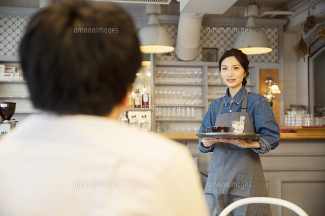 カフェで接客をする女性店員と男性客 の写真素材 イラスト素材 アマナイメージズ