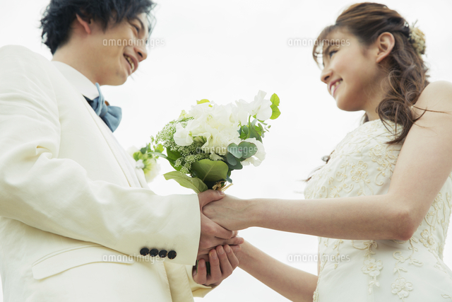 手を取り合い見つめ合う新郎新婦 の写真素材 イラスト素材 アマナイメージズ