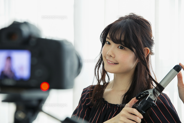 髪を巻く動画撮影をする笑顔の代女性 の写真素材 イラスト素材 アマナイメージズ