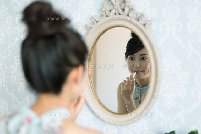 鏡の前で口紅をつける女性 の写真素材 イラスト素材 アマナイメージズ
