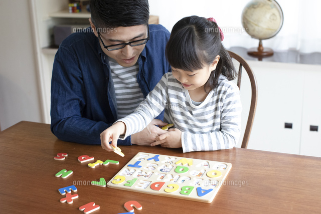 アルファベットのパズルをする女の子とそれを手伝う父親 の写真素材 イラスト素材 アマナイメージズ