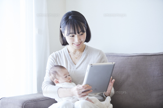 赤ちゃんを抱っこしながらタブレットpcを見る母親と赤ちゃん の写真素材 イラスト素材 アマナイメージズ