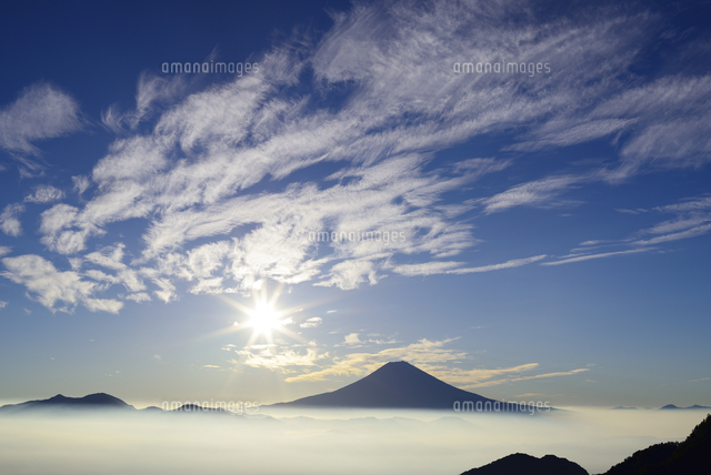 賑やかな雲が舞う空と朝日の中にある富士山 の写真素材 イラスト素材 アマナイメージズ