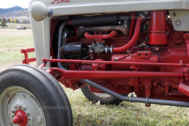 赤いエンジン部が見える薄い灰色のアンティック農作業用トラクターのサイドビュー の写真素材 イラスト素材 アマナイメージズ