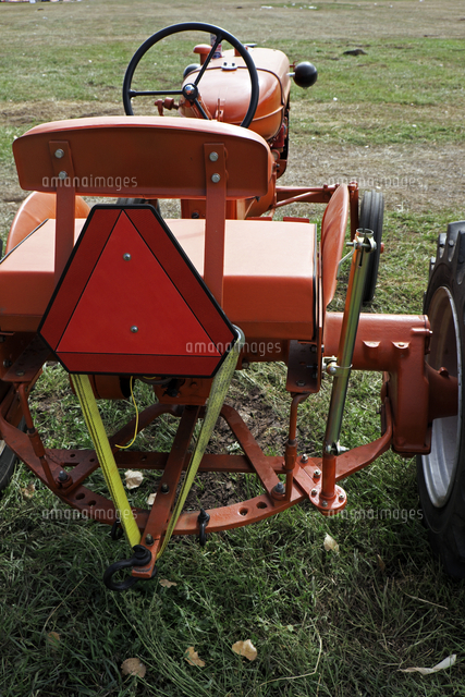草地にとめられたオレンジ色のアンティックの農業用トラクターを後部から見たビュー の写真素材 イラスト素材 アマナイメージズ