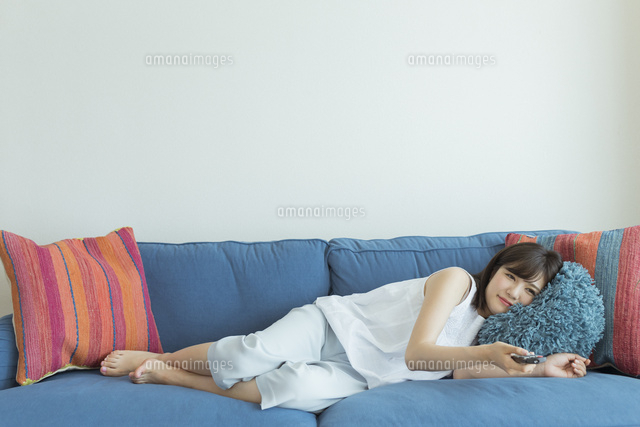 ソファーに横になりテレビを見る女性 の写真素材 イラスト素材 アマナイメージズ