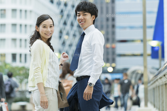 笑顔で振り向く仕事帰りの男女 の写真素材 イラスト素材 アマナイメージズ
