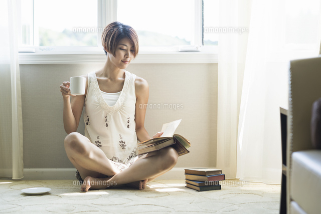 コーヒーを飲みながら読書をする代女性 の写真素材 イラスト素材 アマナイメージズ