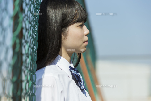 フェンスに寄りかかる女子高校生 の写真素材 イラスト素材 アマナイメージズ