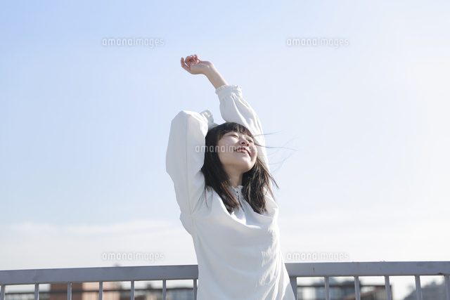 屋上で背伸びをする笑顔の女性 の写真素材 イラスト素材 アマナイメージズ