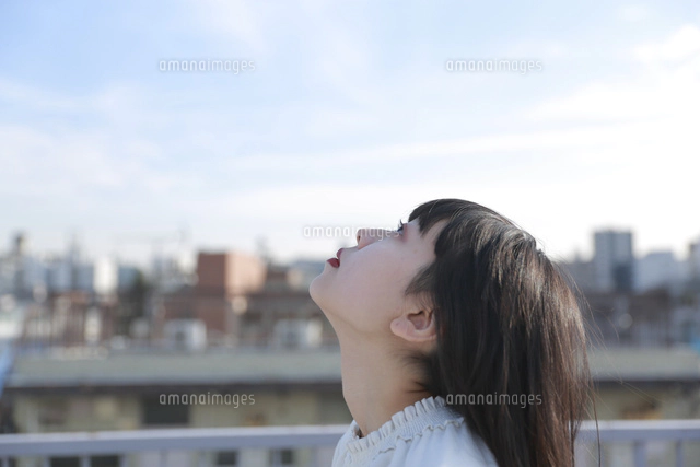 屋上で空を見上げる女性の横顔[10962000095]の写真・イラスト素材