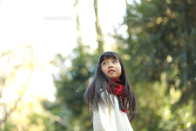 森の中で振り返り空を見上げる女の子 の写真素材 イラスト素材 アマナイメージズ