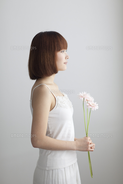 花を持ち横を向いた若い女性 の写真素材 イラスト素材 アマナイメージズ
