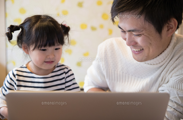 笑顔でパソコンで遊ぶ２０代父と子供 の写真素材 イラスト素材 アマナイメージズ